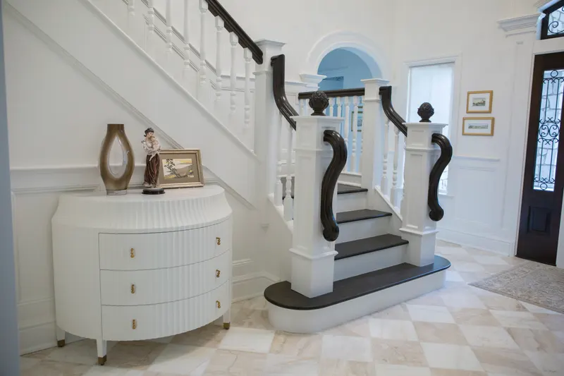 White wood balusters and a dark stained volute handrail in a marble-floored entry
