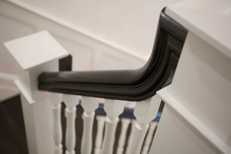 Detail of a dark stained volute where the handrail meets the newel